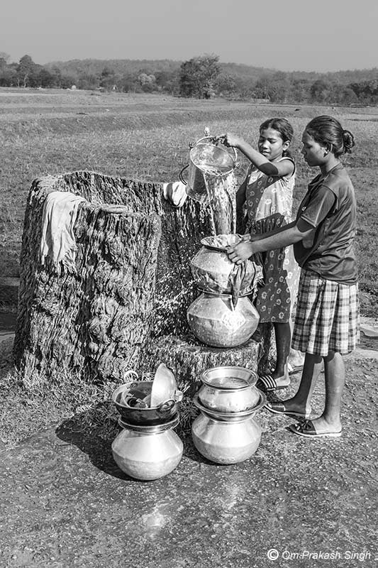 Pots being quickly filled with filtered drinking water at the Kukuru Daarhi in Jiuri village, Jharkhand, India